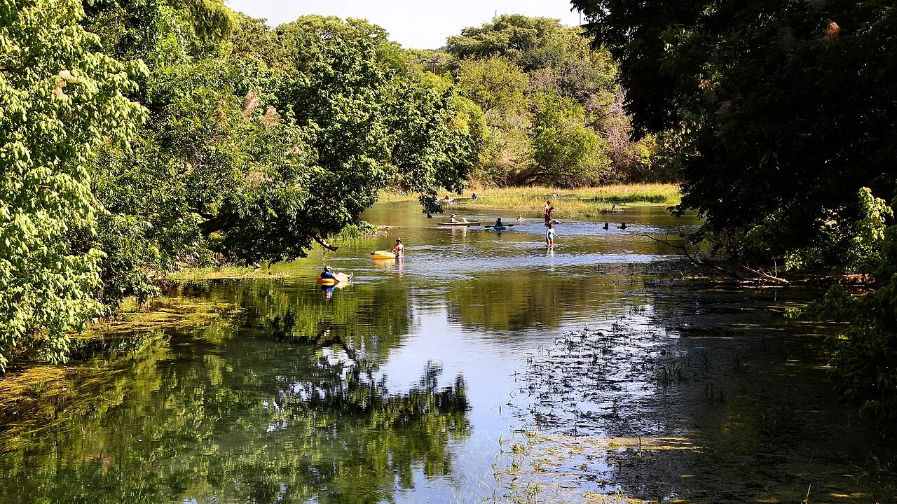 People enjoying the tree-lined San Marcos River in San Marcos, Texas, in 2023